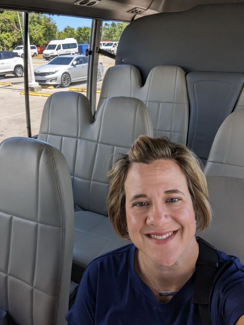 How Much Should I Tip in Europe — and Where's the Best Place to Get My Cash? Smiling woman takes a selfie on a bus, seats and windows visible in the background.
